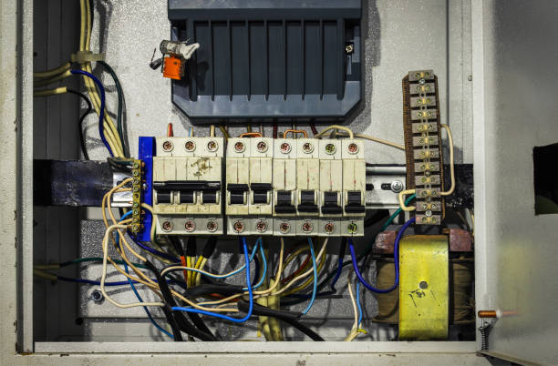Old, disorganized switchboard with tangled wires and circuit breakers, highlighting the need for switchboard upgrades for improved electrical safety.