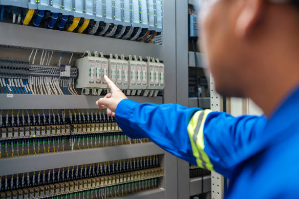 Electrical engineer inspecting a circuit breaker during switchboard upgrades to enhance electrical safety and system reliability.